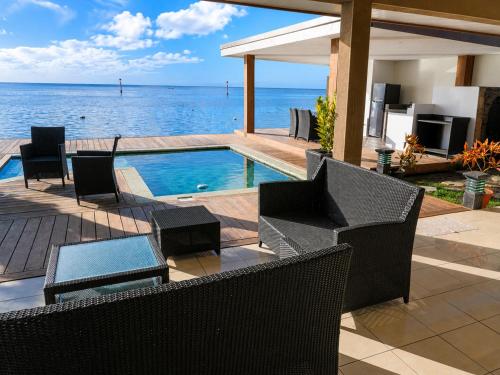 a patio with chairs and a swimming pool overlooking the ocean at Villa Manatini in Papeete