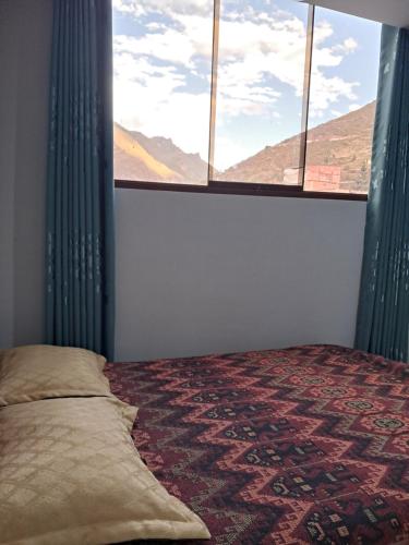 a bedroom with a bed and a large window at Apartamentos Pachatusan in Pisac
