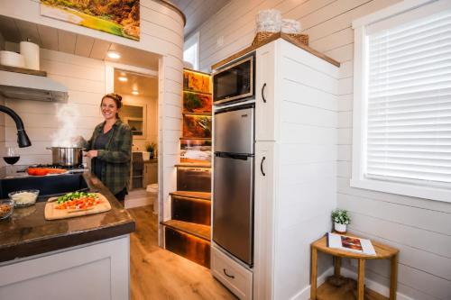 a woman standing in the kitchen of a tiny house at Tiny Home with Private Hot Tub, Zion Adventure Base in Apple Valley