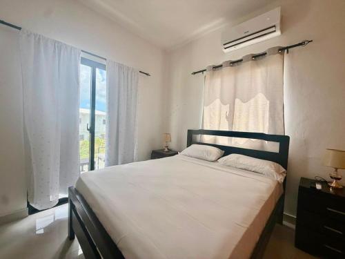 a bedroom with a bed with white sheets and a window at Paradise Cove in Punta Cana