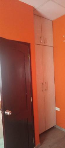 an orange room with a door and some cabinets at Los Ceibos Hostal in Montecristi