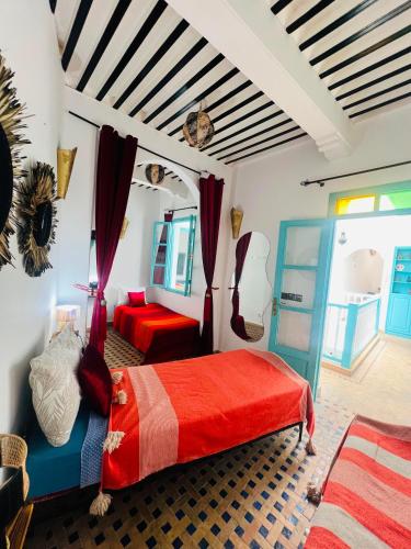 a bedroom with a bed with a red blanket at Riad Darko in Essaouira