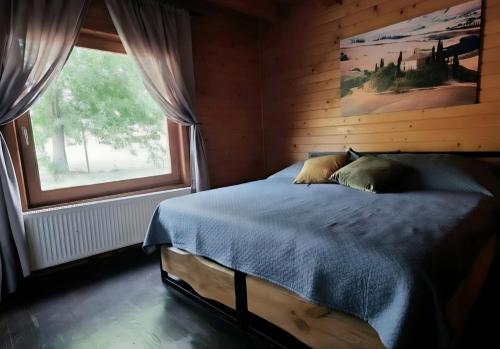 a bedroom with a bed and a large window at Komondor Vendégház in Vácrátót