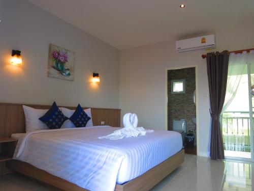 Un dormitorio con una cama blanca con una toalla. en Winrisa Place, en Nai Yang Beach