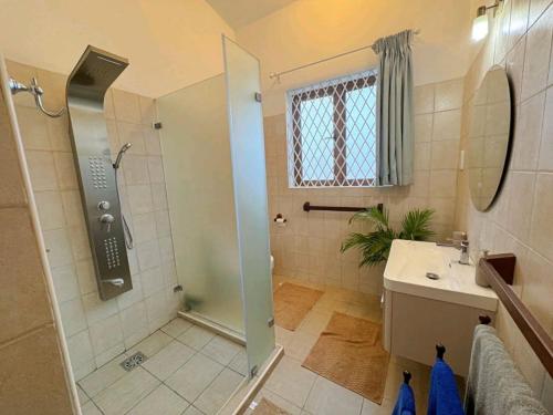 a bathroom with a shower and a sink at Palm Villa Hideaway in Diani Beach