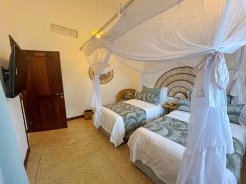 a bedroom with two beds and a canopy at Palm Villa Hideaway in Diani Beach
