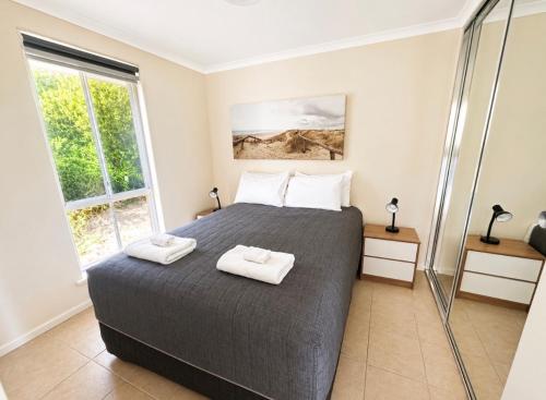 a bedroom with a bed with two towels on it at Robe Sunset Apartments in Robe