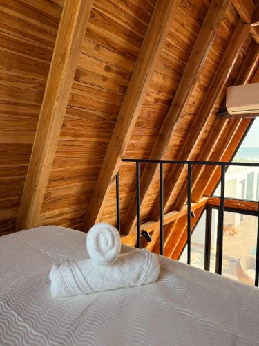 a bed in a room with a wooden ceiling at Helite Arena y Mar in Puerto Cayo