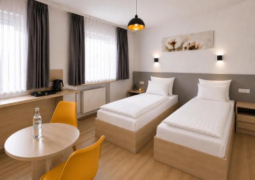 a hotel room with two beds and a table at Hotel Central Nürnberg Hauptbahnhof in Nuremberg