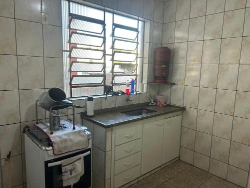 a small kitchen with a sink and a window at Apartamento simples no centro de Lavras com garagem in Lavras