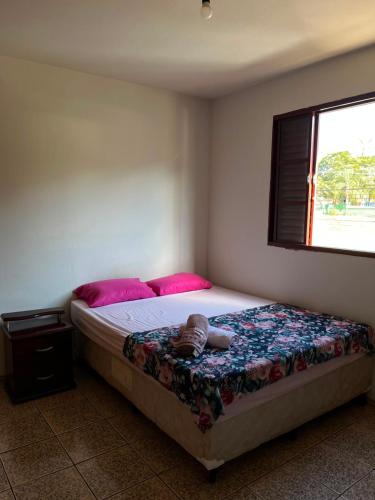 a bedroom with a bed with pink pillows at Apartamento simples no centro de Lavras com garagem in Lavras