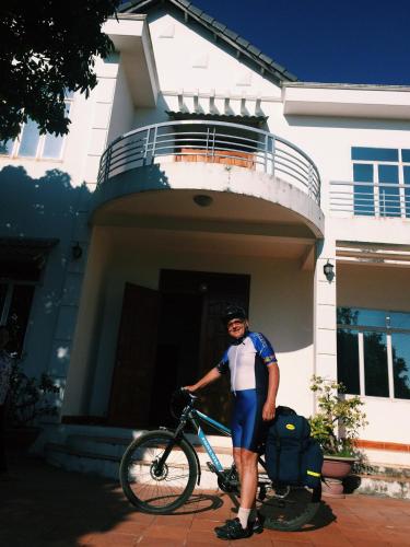 a man standing with a bike in front of a house at Vietnam Phuot Real Home in Kon Tum