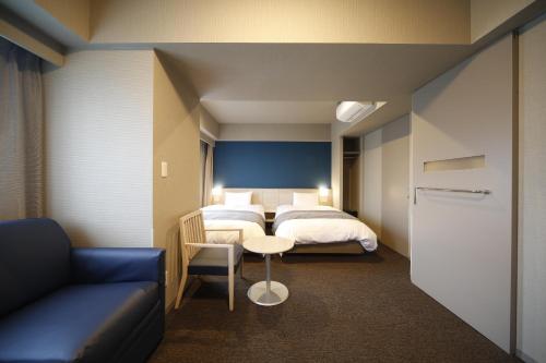 a bedroom with a bed and a table and a couch at Dormy Inn Miyazaki Natural Hot Spring in Miyazaki