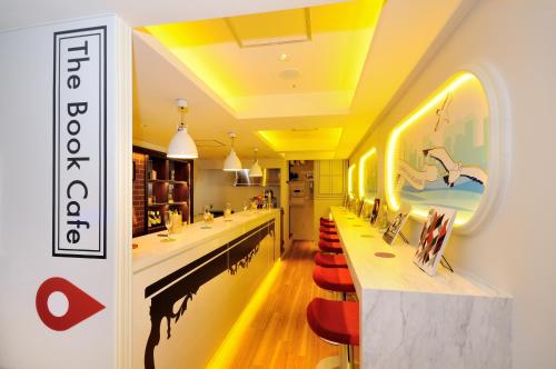 a restaurant with a long bar with red stools at Spa&Capsule Hotel Grandpark Inn Kitasenju in Tokyo