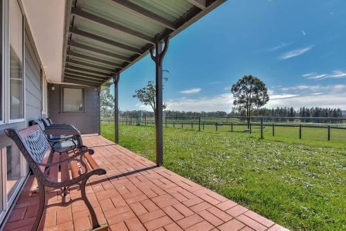 a porch with a bench and a field of grass at Andres Farm Cottage in Broke