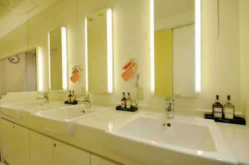 two sinks in a bathroom with two mirrors at Spa&Capsule Hotel Grandpark Inn Kitasenju in Tokyo