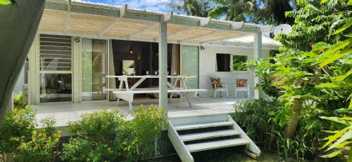 a patio with a table and chairs and a pergola at Cottage Manua in Temae