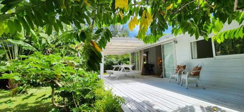 a porch of a white house with a table and chairs at Cottage Manua in Temae