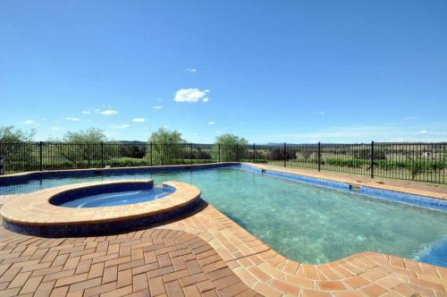 a swimming pool with a patio and a fence at Beggars Bridge Vineyard Homestead with pool and tennis in Rothbury