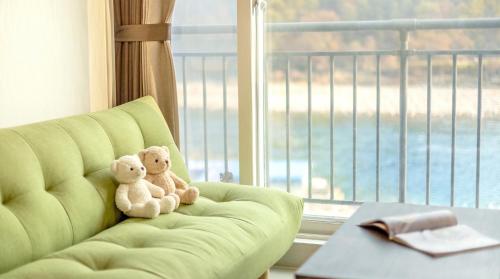 two teddy bears sitting on a couch in front of a window at Gapyeong Rialto Pension in Gapyeong