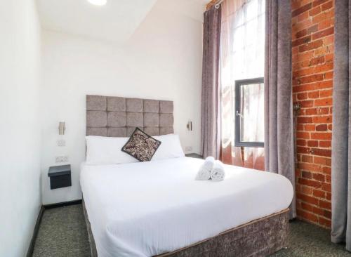 a bedroom with a white bed and a brick wall at Kick back relax stylish space in Nottingham
