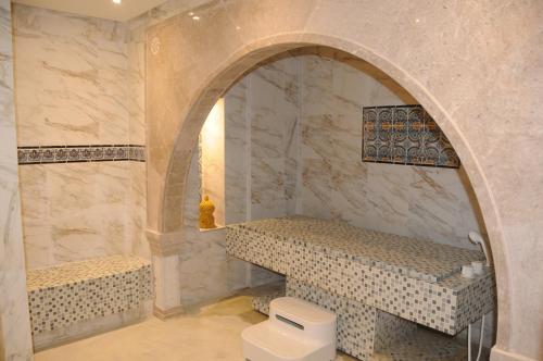 a bathroom with a toilet and a stone wall at Hotel Menara in Hammamet