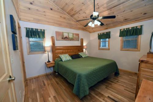 a bedroom with a green bed and wooden floors at 6BR/5BA Retreat • Hot Tub • Game Room • Treehouse in Blue Ridge