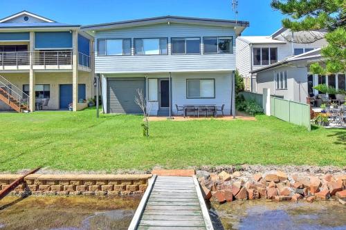 a house with a wooden walkway in front of a yard at Balmoral Waterfront Escape at Lake Macquarie in Balmoral