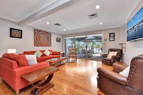 a living room with a red couch and chairs at Wangi Dreaming in Wangi Wangi