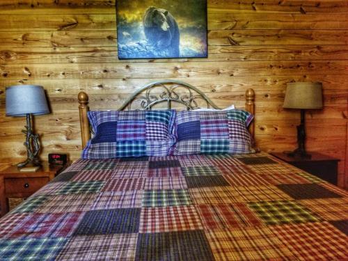 a bedroom with a bed with a plaid blanket and two lamps at 2BR/1BA Cabin | Hot Tub | Ocoee River Area | Wifi in Copperhill