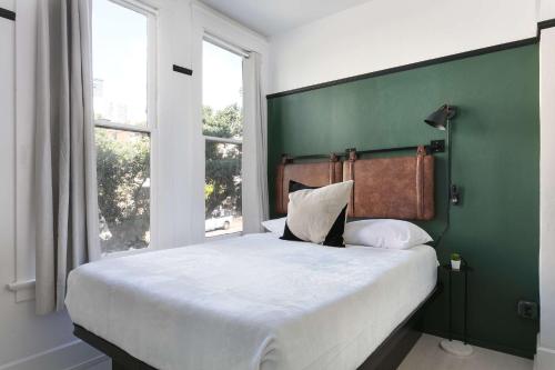 a bedroom with a large bed with a green headboard at 1BR Escape Queen Bed WiFi & Kitchenette in San Diego