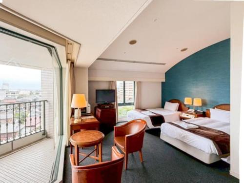 a hotel room with two beds and a balcony at Hotel LiVEMAX Nagasaki Airport in Omura