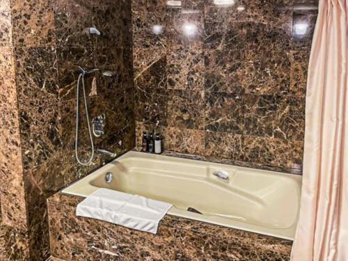 a bathroom with a tub and a shower at Hotel LiVEMAX Nagasaki Airport in Omura