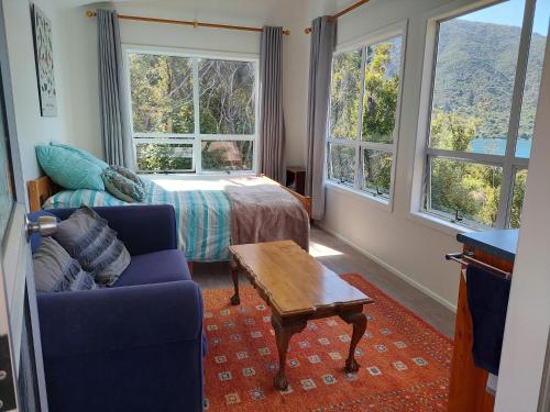 a living room with a couch and a bed and windows at Endeavour View Eco Cabin in Endeavour Inlet