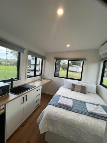 a bedroom with a bed and a sink and windows at BIG4 Sale Caravan Park in Sale