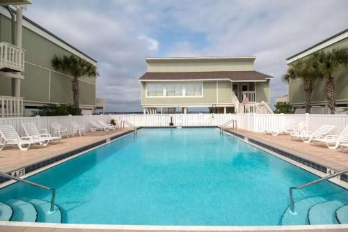 a swimming pool with chairs and a house at Sound-Side Condo with Grill Deck & W&D and Shared Pool in Pensacola Beach