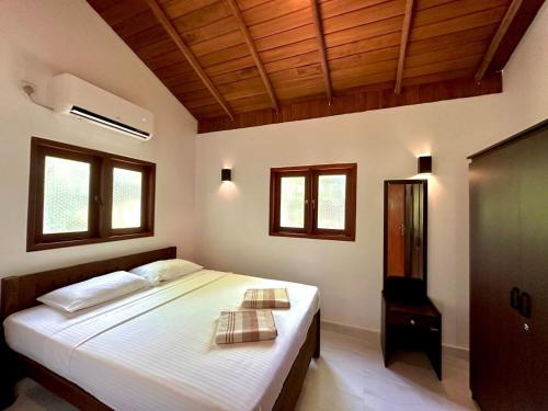 a bedroom with a bed with white sheets and windows at Body,Mind & Soul in Bentota