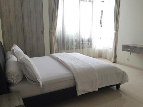 a bedroom with a white bed with a window at Roemah Asri Villa - Resor Dago Pakar in Bandung