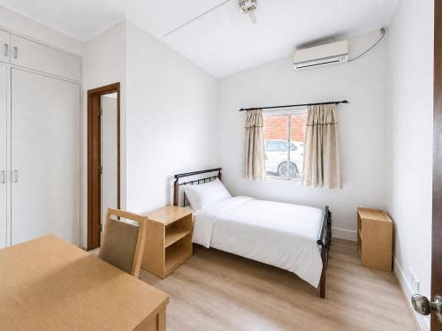 a bedroom with a bed and a desk and a window at Box Hill Student Accommodation and Rooming House in Box Hill
