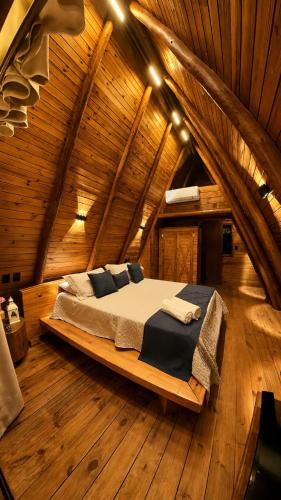 a bed in the middle of a wooden room at Chalé Suíco Vale do Capão in Palmeiras