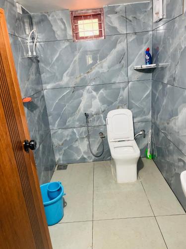 a bathroom with a white toilet in a room at CHRIS COZY FARM cottage in Wayanad