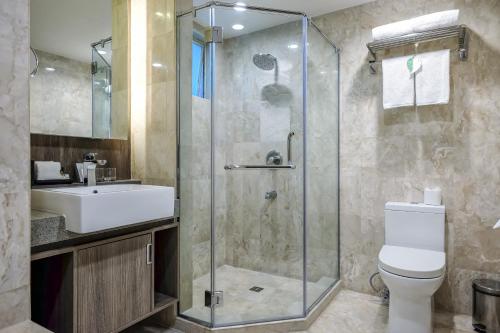 a bathroom with a shower and a toilet and a sink at Somerset Millennium Makati in Manila