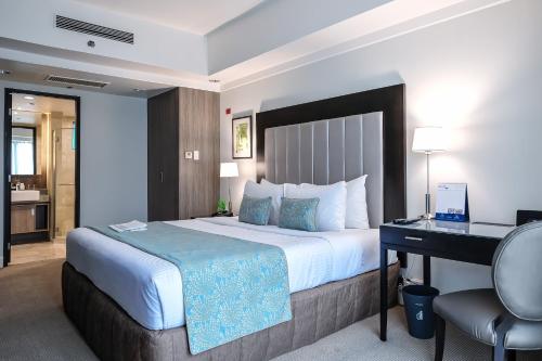 a hotel room with a large bed and a desk at Somerset Millennium Makati in Manila