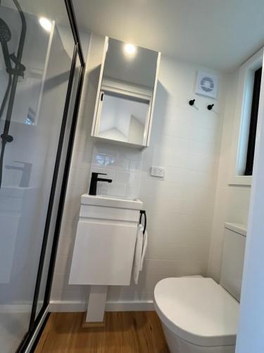 a white bathroom with a toilet and a sink at BIG4 Sale Caravan Park in Sale