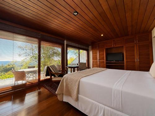 a bedroom with a large bed and a large window at Hortênsia Boutique - Chalés de Luxo & Suítes Privativas in Campos do Jordão