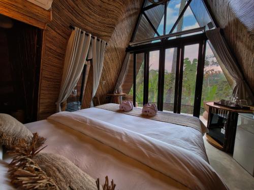 a bedroom with a large bed with a large window at Delta Casa Ubud - A-Frame Jungle Retreat with Volcano View and Hot-Tubs in Gianyar