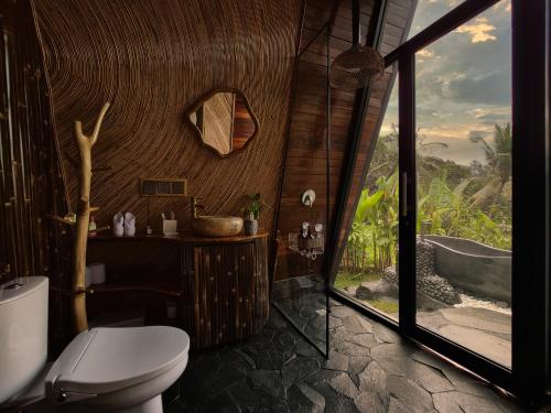 a bathroom with a toilet and a bath tub at Delta Casa Ubud - A-Frame Jungle Retreat with Volcano View and Hot-Tubs in Gianyar