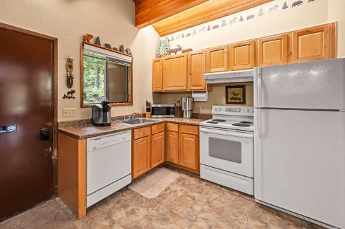 a kitchen with white appliances and wooden cabinets at Limber Pine Townhome and 2BDR Stay in Whitefish