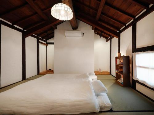 a bedroom with a white bed and a chandelier at 眠ル庭ーnemuruniwa in Tochigi