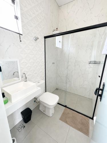 a bathroom with a shower and a toilet and a sink at Alphaville Studios in Pirapora